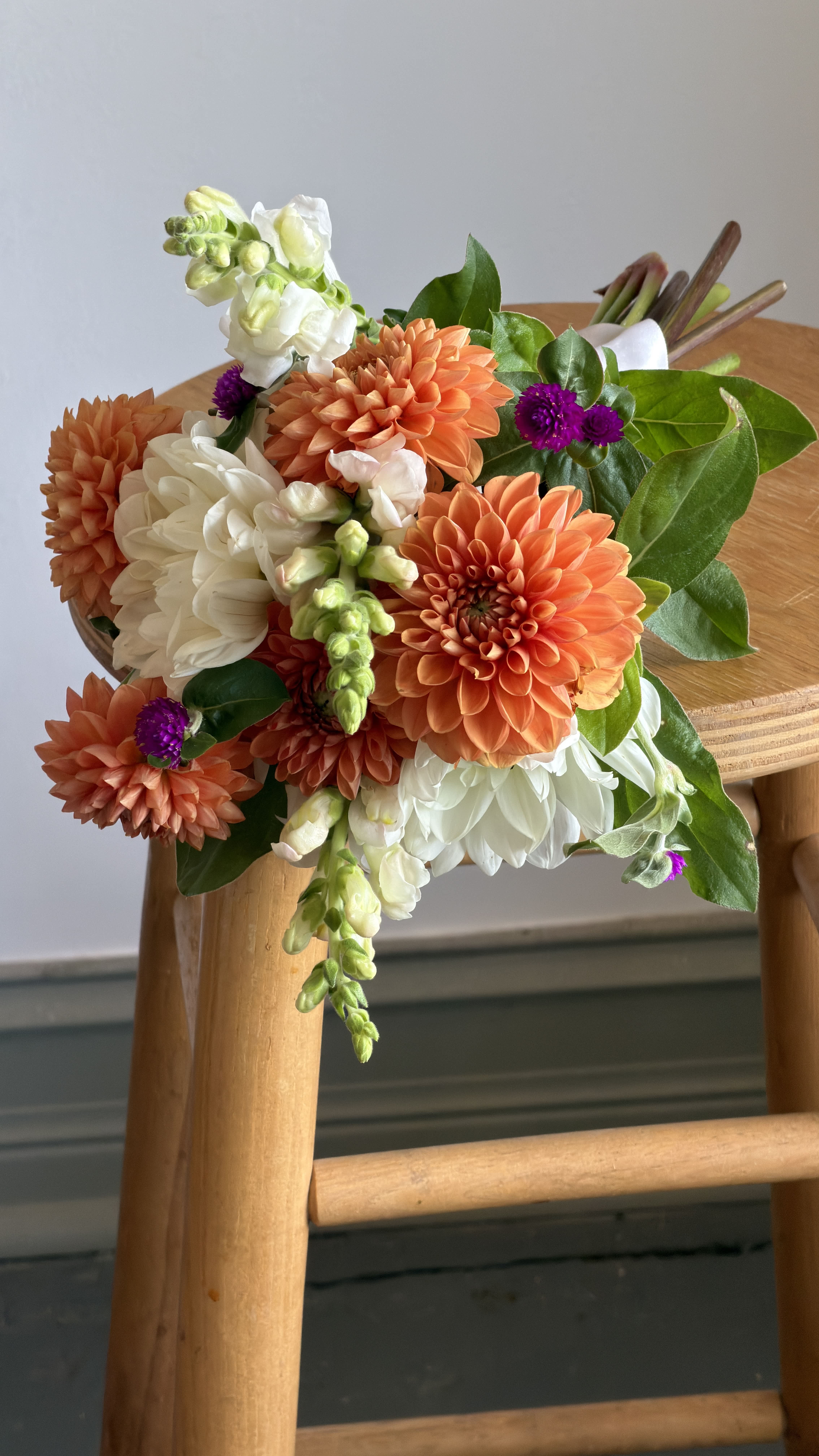 Bouquet of orange and white flowers with green leaves on a wooden chair