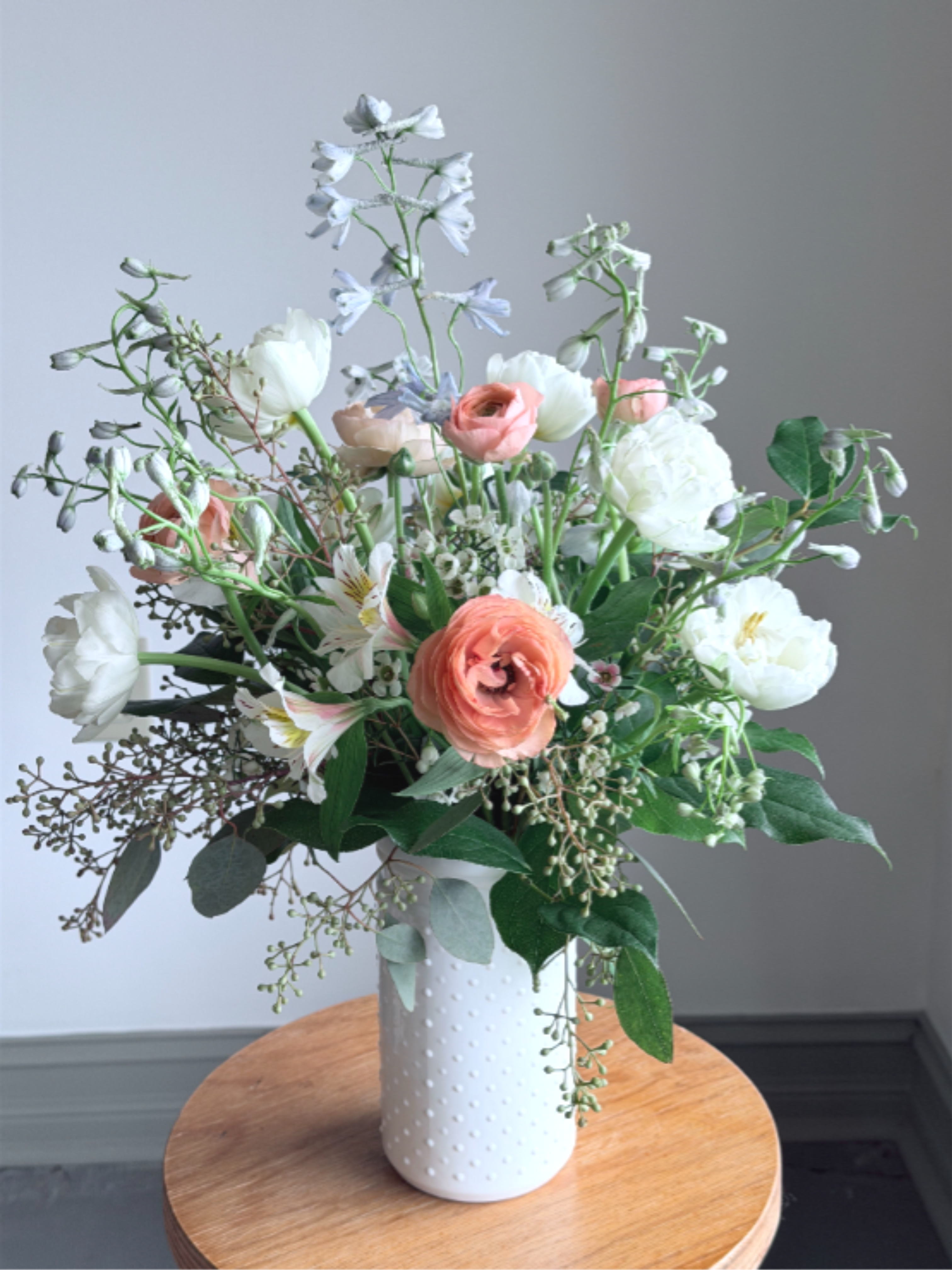 Spring Series - Pastel Vase - There is nothing more welcoming than the signs of spring. Share this soft pastel mix with someone on your mind. Simply arranged in a hobknob vase filled with flowers such as  ranunculus, tulips, delphinium, peony or other spring essentials.    Arrangement is approximately 20" h x 12" w  All of our flowers are seasonal, locally sourced and American grown. This allows you to receive the most fresh, seasonal flowers possible for a longer lasting bouquet or arrangement. Each arrangement produced is unique to the season and may contain different flowers than what are listed here. 
