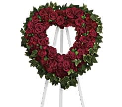 Heart-shaped wreath of red roses on a white easel