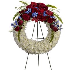 Standing floral wreath with red and white flowers on an easel