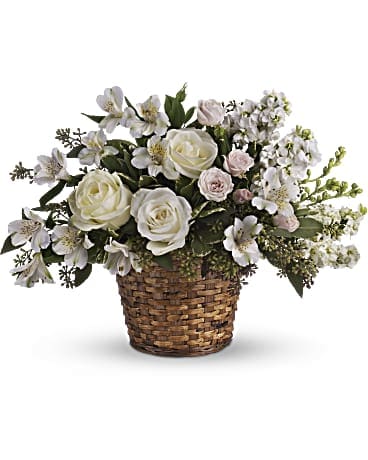 White roses and small white flowers in a woven basket