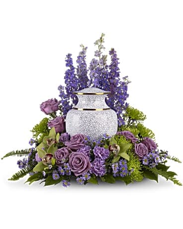 Purple floral arrangement around a white urn vase
