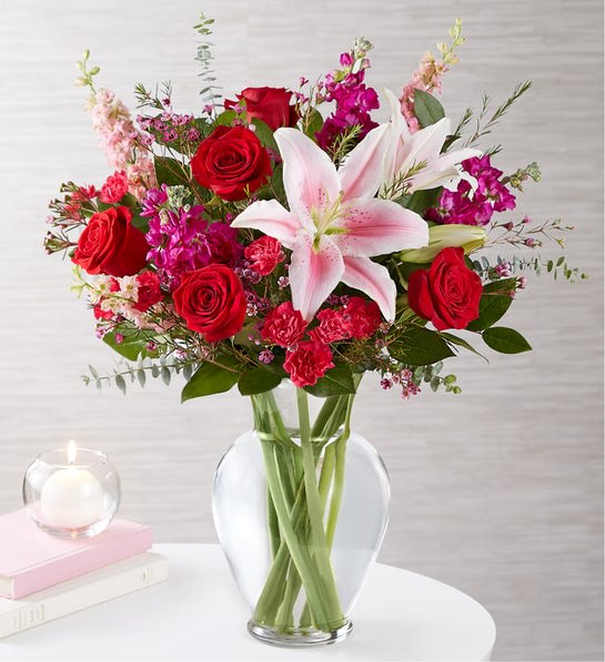 Bouquet of red roses and pink lilies in a clear glass vase