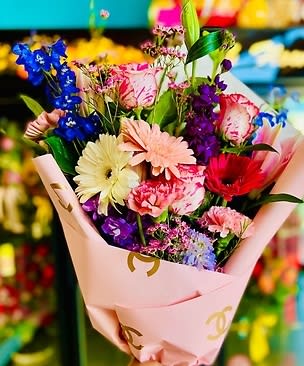 Mixed bouquet with gerbera daisies, carnations, and purple flowers in pink wrap