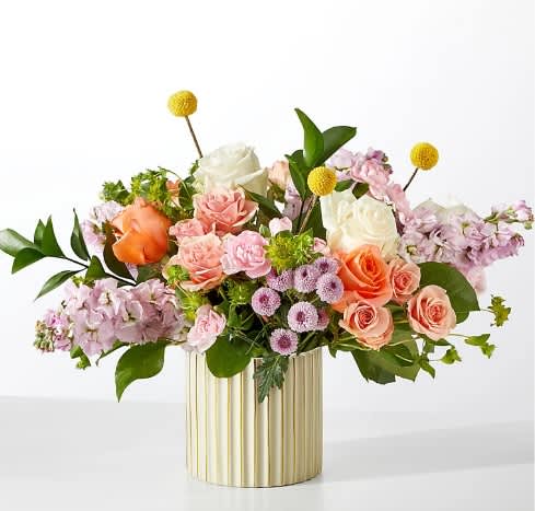 Mixed bouquet of roses and pastel flowers in a gold ribbed vase