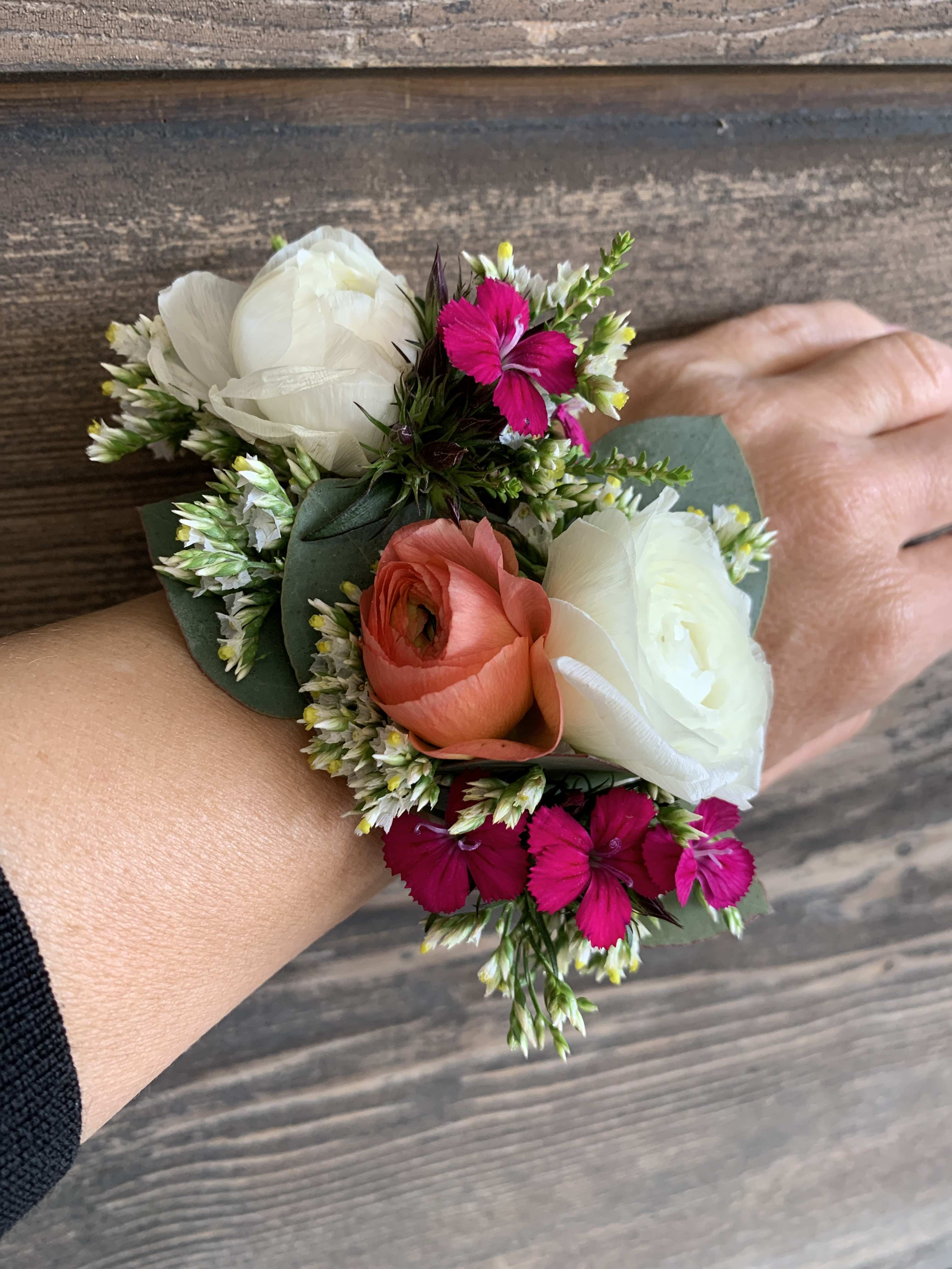 Small wrist corsage with white, coral, and bright pink flowers