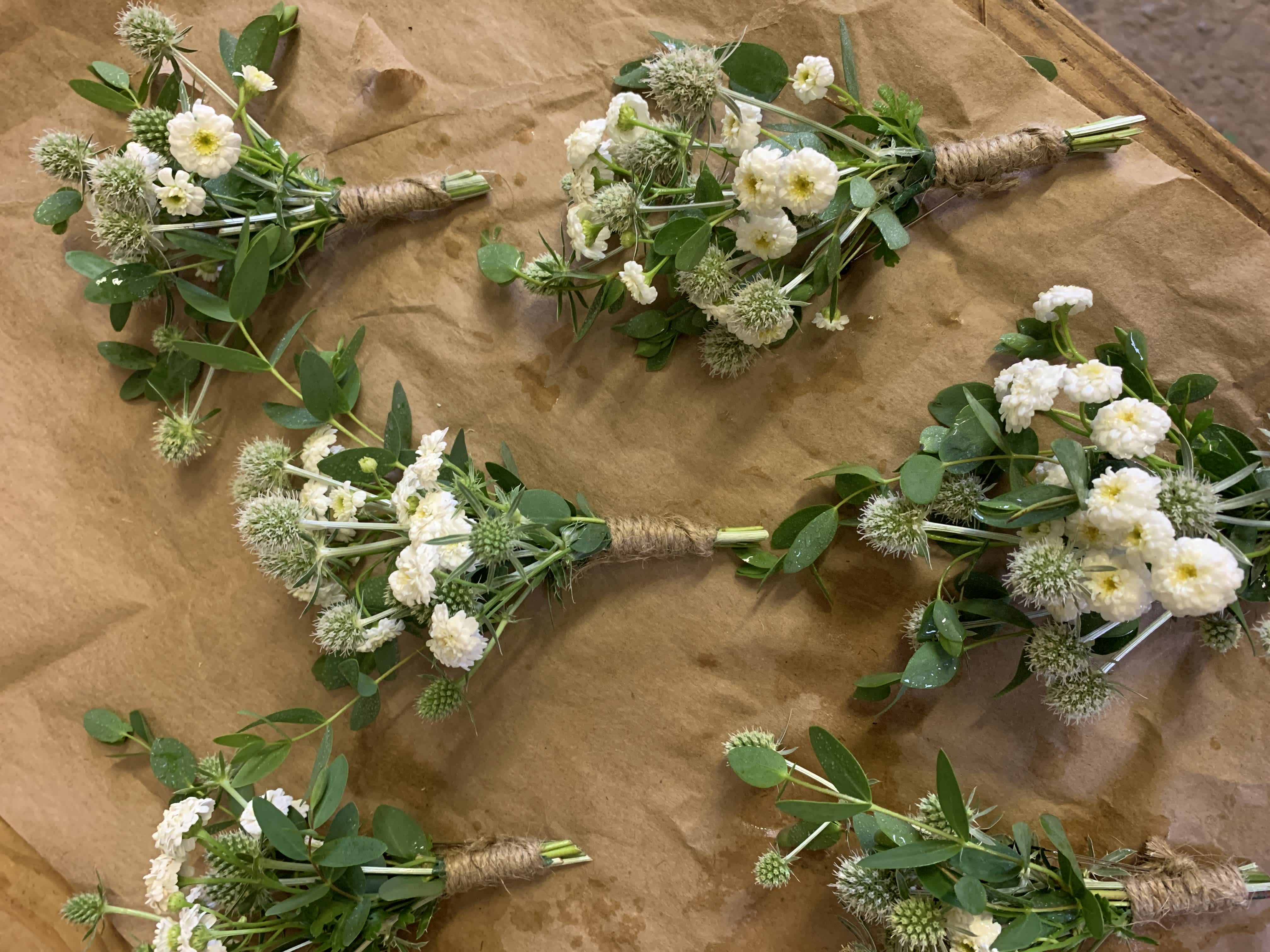 Small white flower bouquets with green foliage wrapped in twine