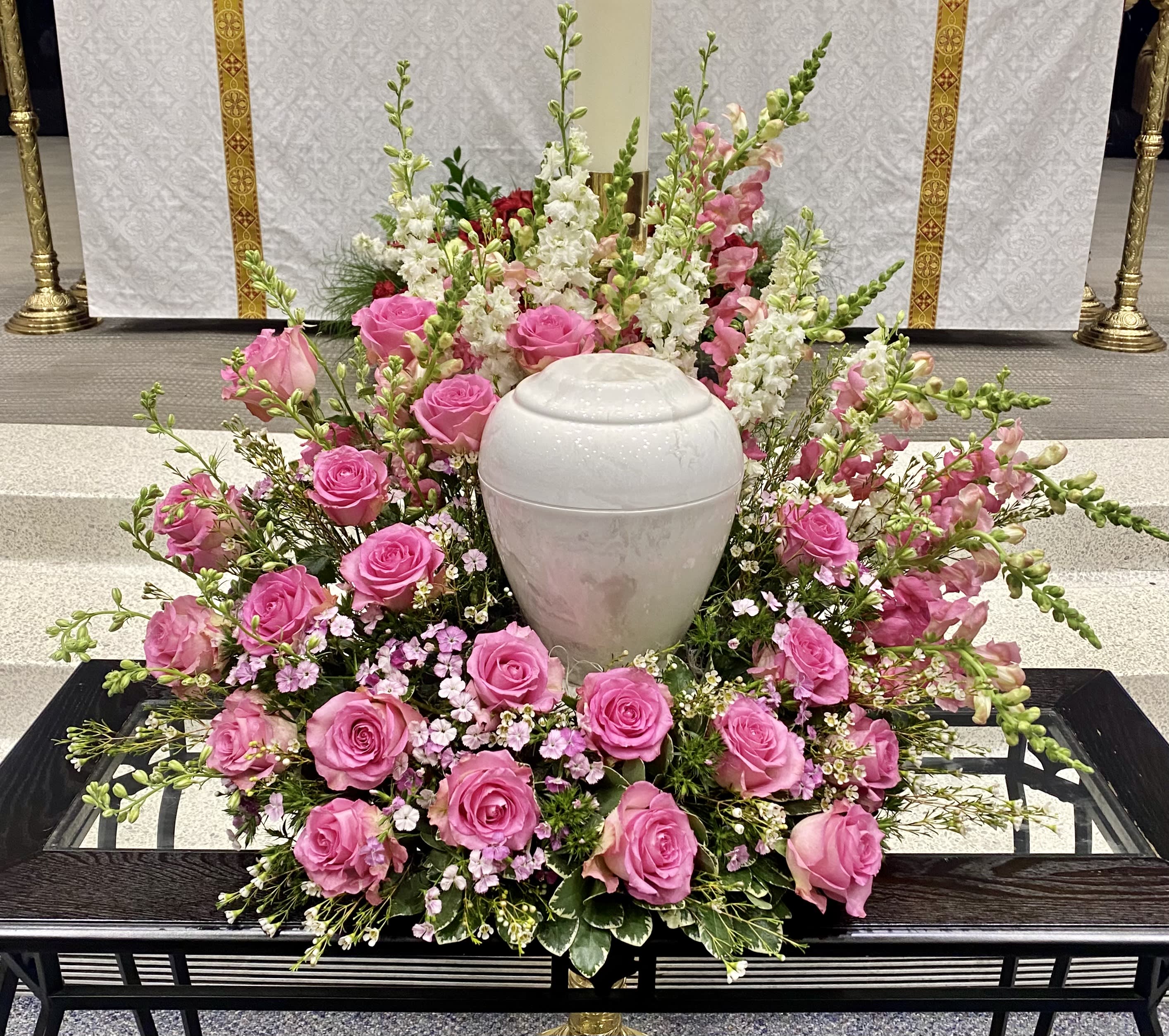 Pink roses and white snapdragons arranged around a white urn