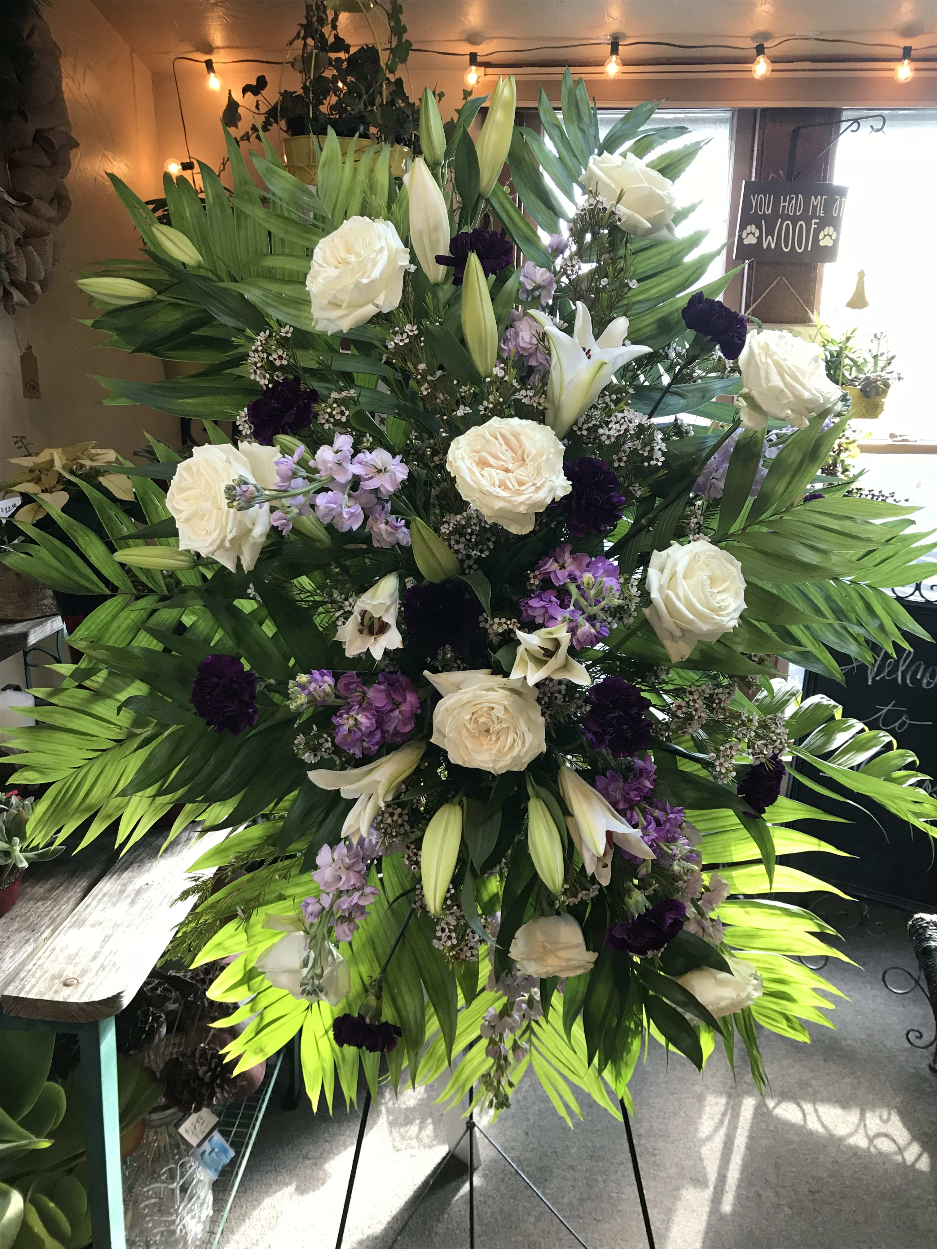 Tall standing floral spray with white roses, lilies, and purple accents