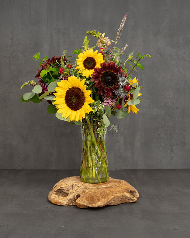 Sunflower bouquet in a clear glass vase on a wooden base