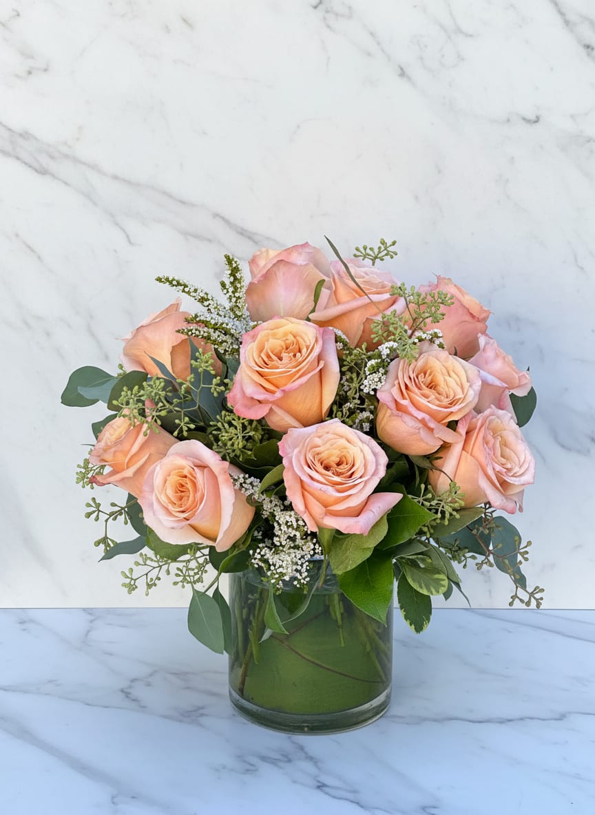 Peach Roses - Peach Roses — A timeless and elegant arrangement featuring premium peach roses accented with lush greenery and delicate white filler flowers. This classic bouquet radiates warmth and grace, perfect for anniversaries, birthdays, or simply brightening someone’s day. Arranged in a clear glass vase, Peach Roses brings a soft, romantic touch to any setting. Handcrafted with care by our San Francisco florist for same-day delivery.