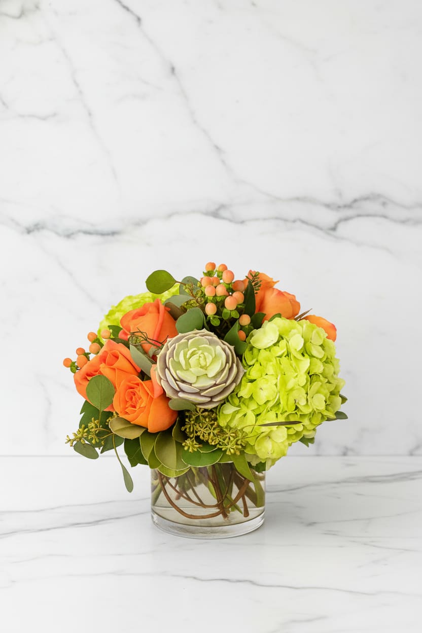 Sunset in San Francisco - Radiant and full of charm, Sunset in San Francisco captures the warmth of a coastal evening with lush orange roses, green hydrangeas, and a striking succulent centerpiece. Designed in a clear glass vase with natural textures and soft greenery, this arrangement blends modern elegance with natural beauty. Perfect for celebrations, thank-yous, or simply brightening your space.  Warm. Modern. Designed with love in San Francisco by Polk Street Florist.