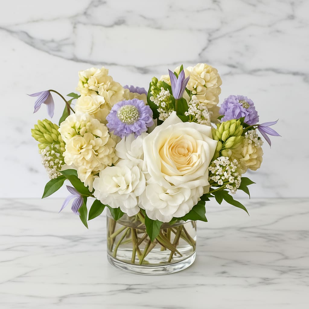 White and lavender flowers arranged in a clear glass vase