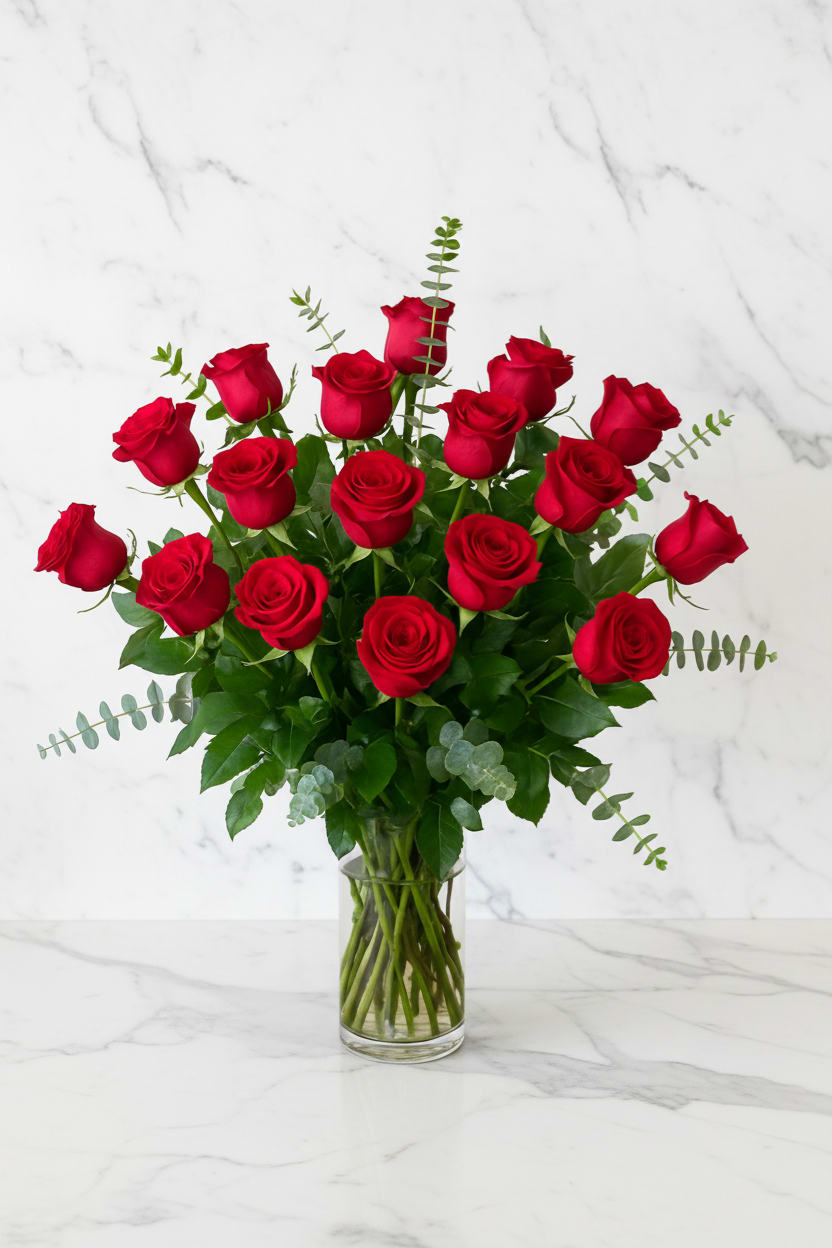 Red roses arranged in a clear glass vase with greenery
