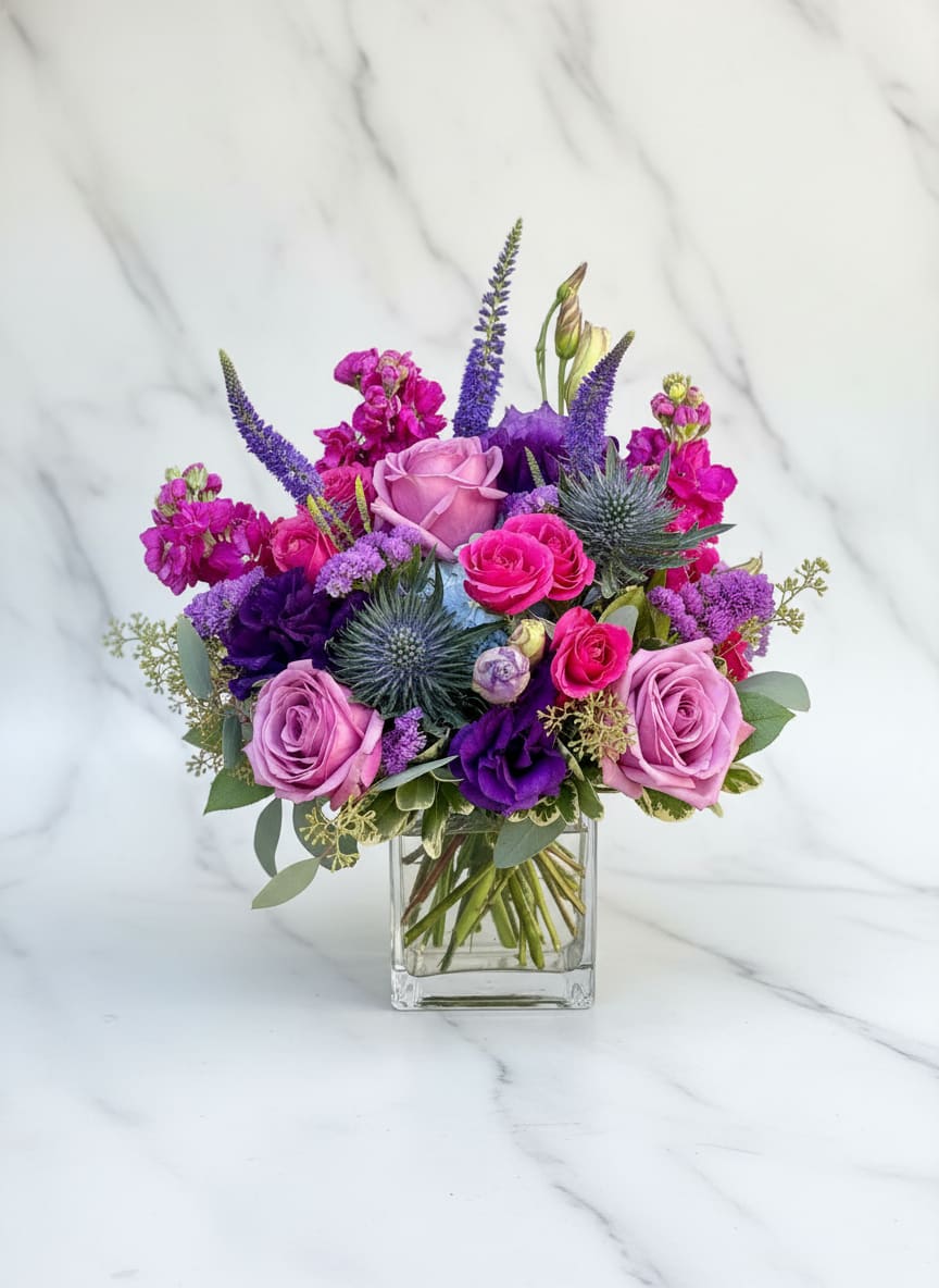 Purple and pink rose bouquet in a clear glass vase
