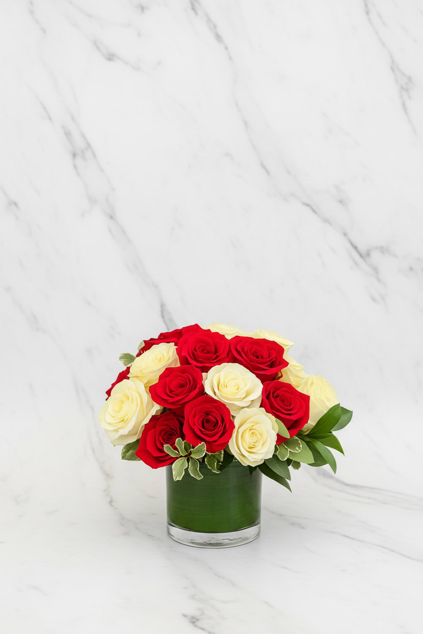 Red and White Roses - Classic and romantic, Red and White Roses features a stunning mix of premium blooms arranged in a modern glass vase. The deep red roses symbolize love and passion, while the creamy white roses represent purity and grace — a perfect balance for any occasion. Thoughtfully designed with lush greenery, this arrangement adds timeless elegance to any space.  Elegant. Refined. Designed with love in San Francisco by Polk Street Florist.  