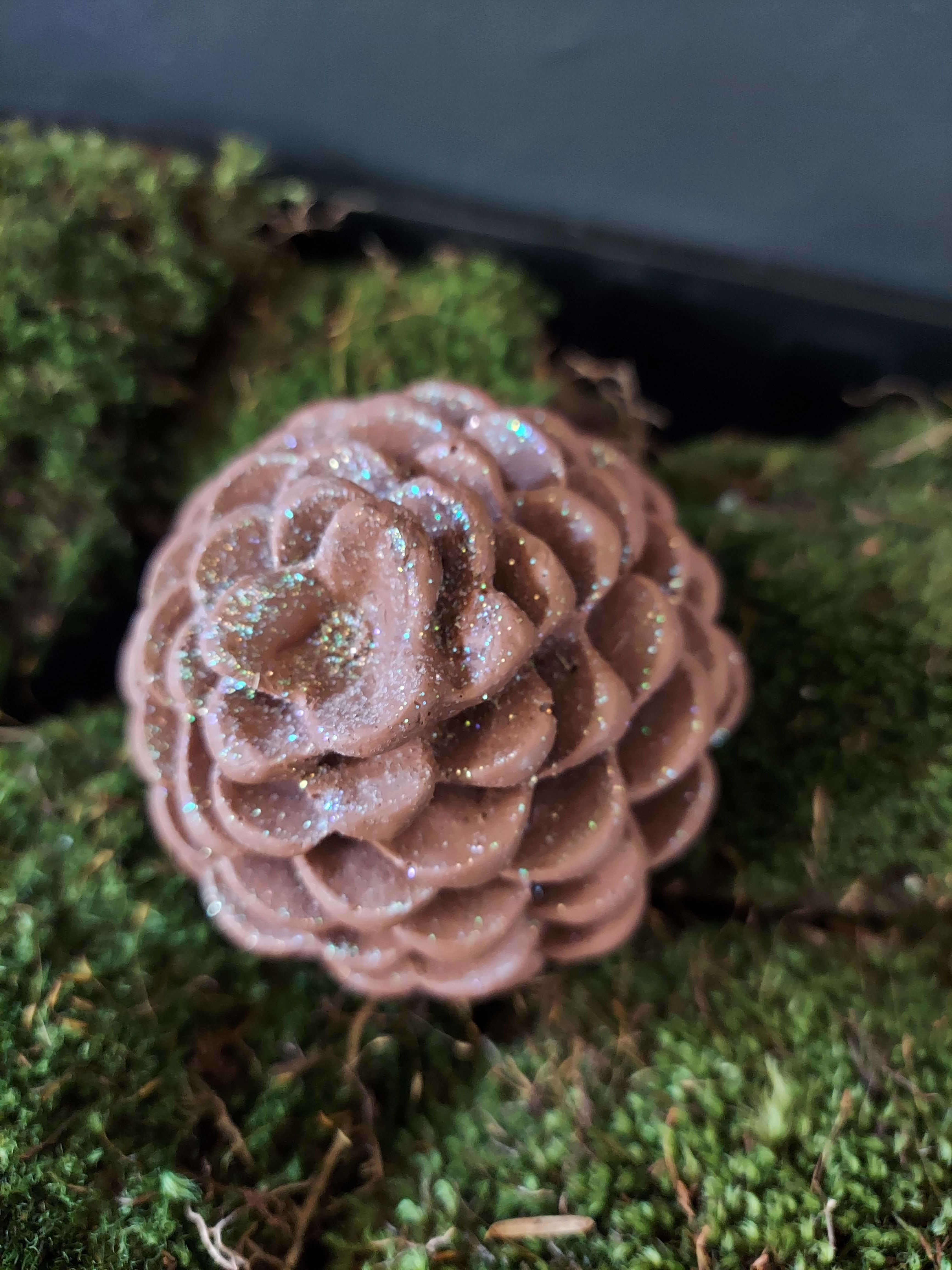 Glittery pine cone resting on moss