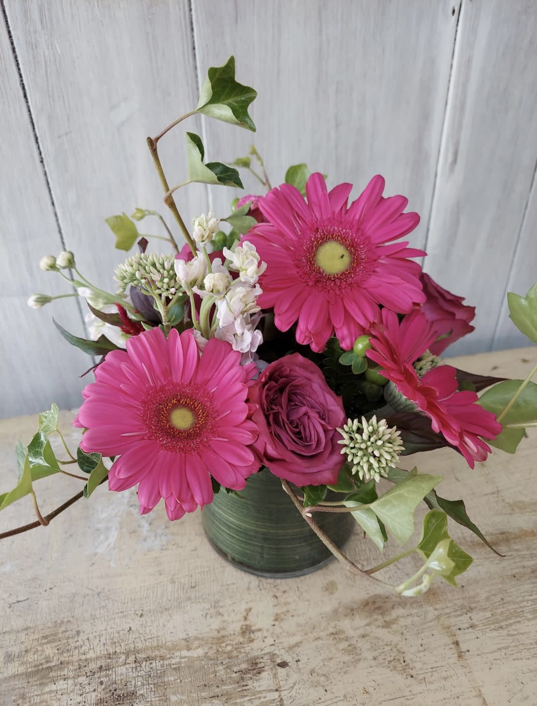 Pink gerbera daisies and roses in a green vase