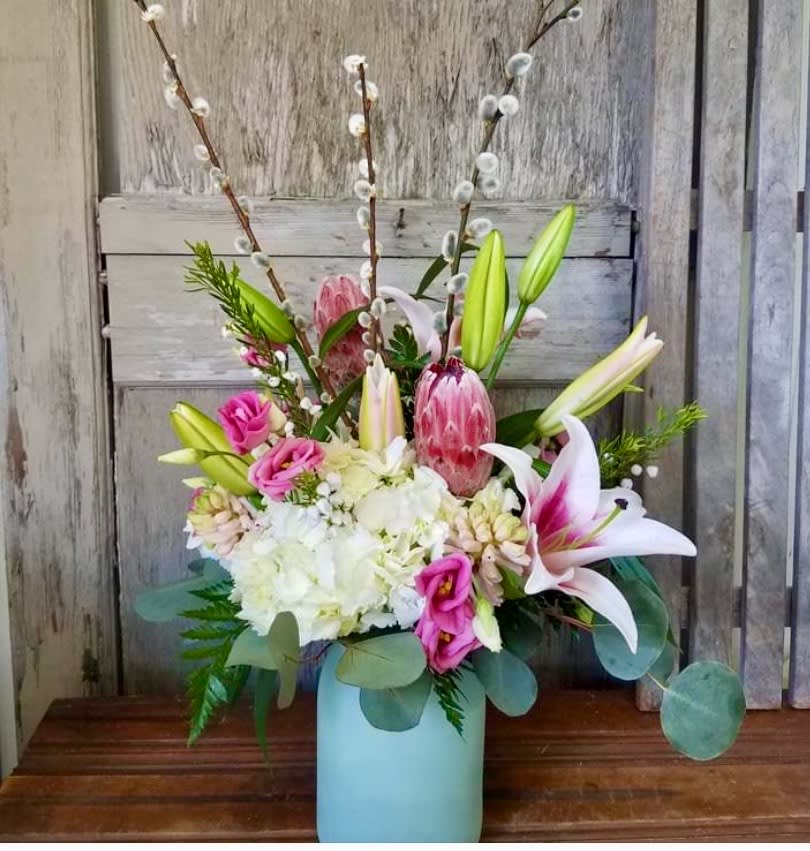 Pink lilies and roses in a blue vase with white hydrangeas