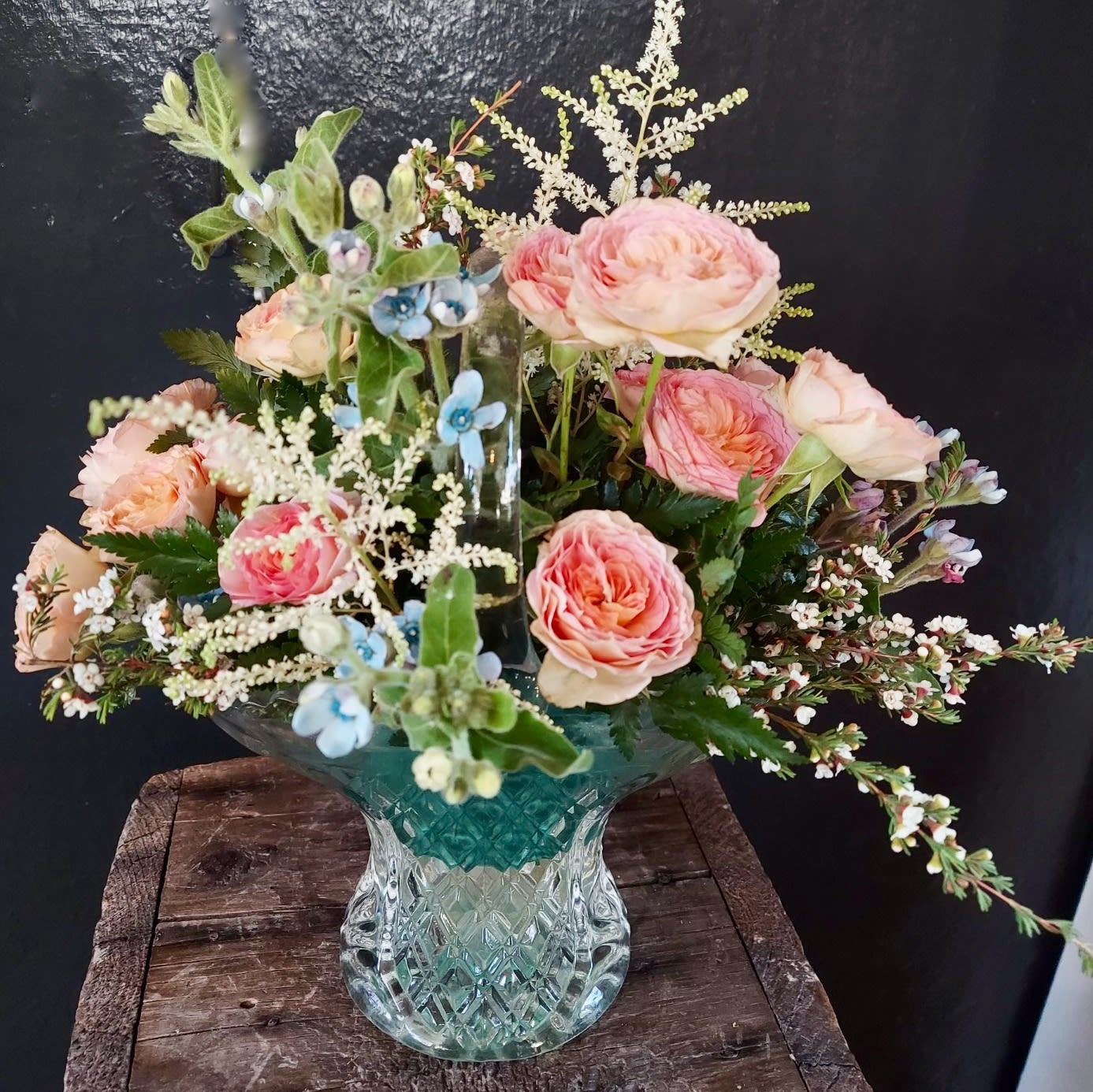 Pink roses in a glass vase with blue accent flowers