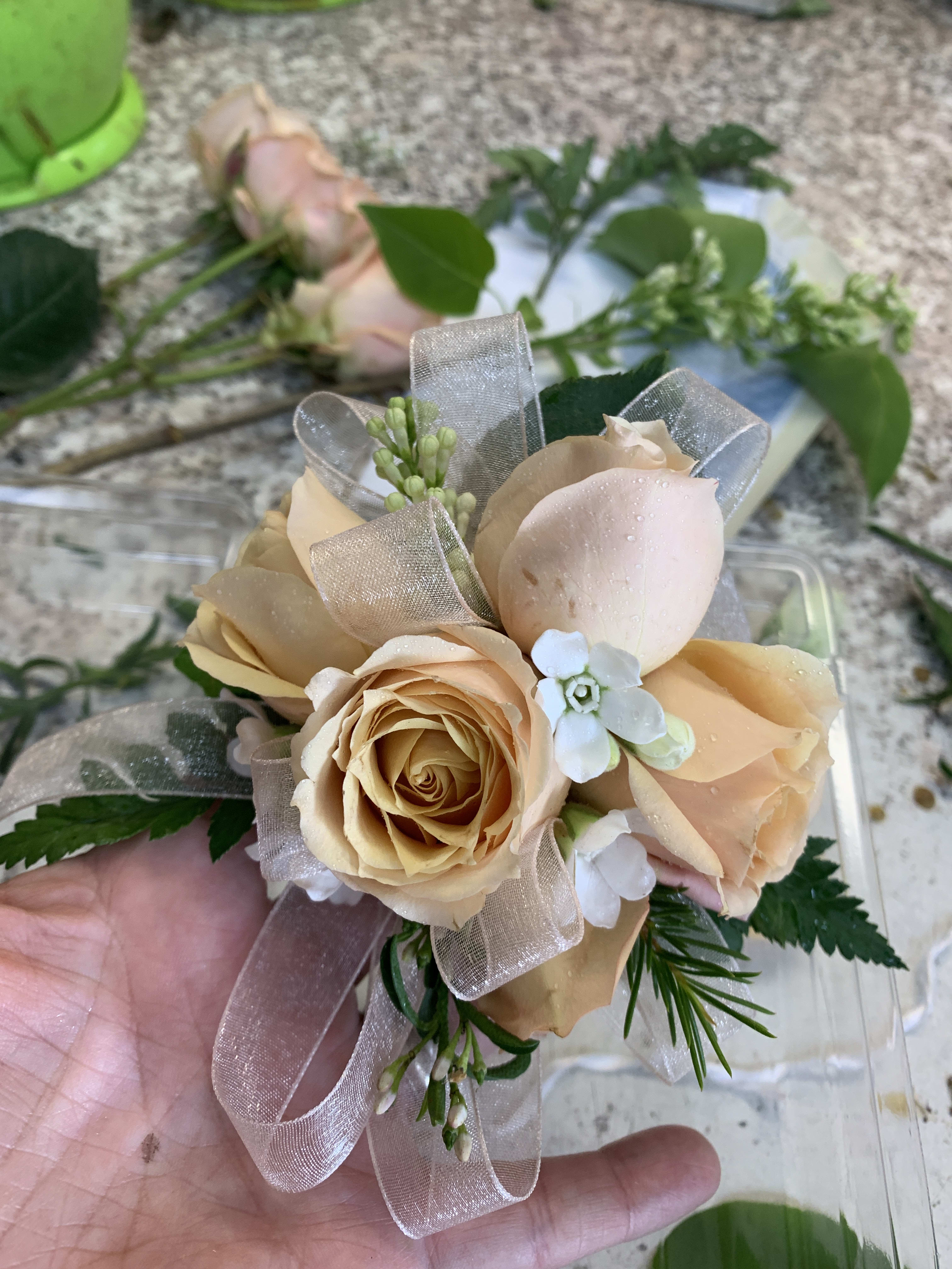 Small bouquet of peach roses with ribbon and greenery