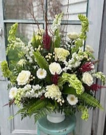 Large white and green floral arrangement in a white vase