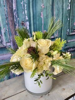 Cream floral arrangement in a white vase with long greenery accents