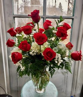 Bouquet of red roses and white filler flowers in a clear glass vase