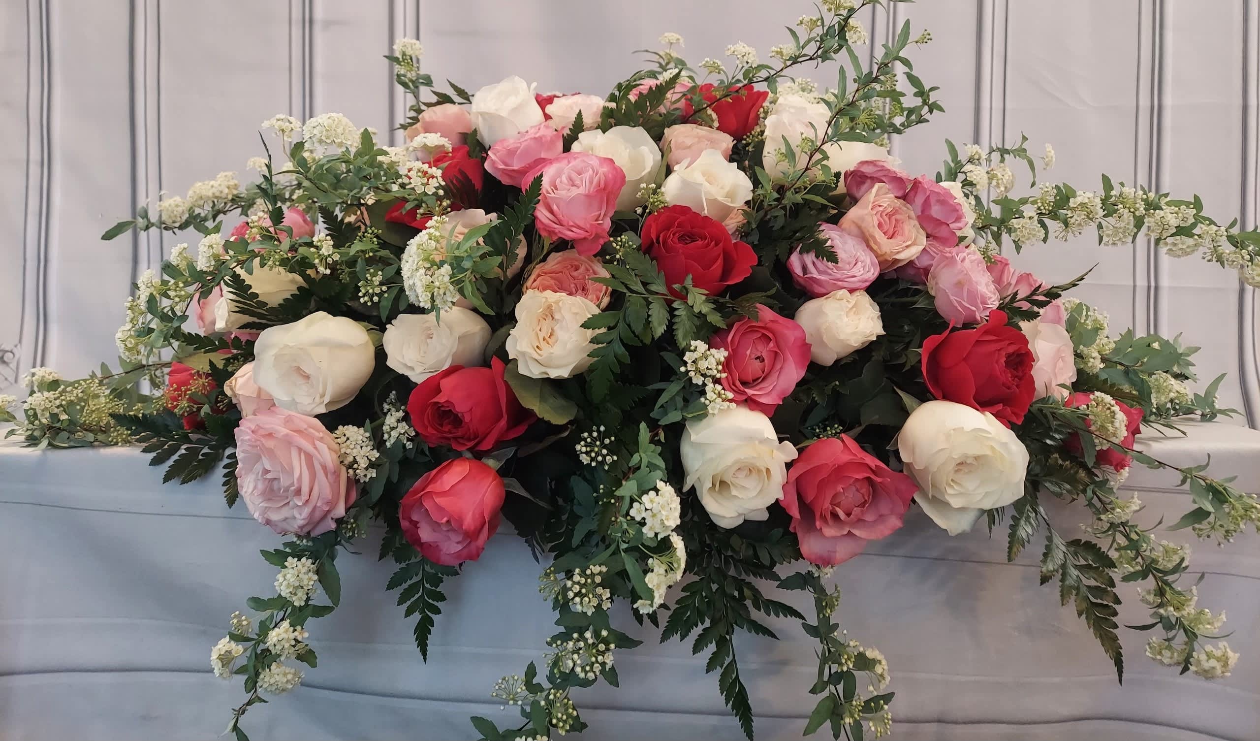 Large arrangement of pink, red, and white roses with trailing greenery