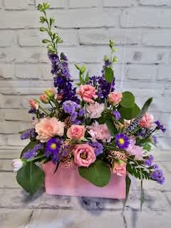 Pink and purple mixed flower arrangement in a pink box