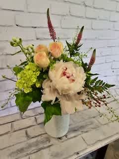 Bouquet of pale peach and white flowers in a white vase