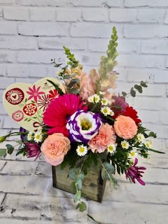Mixed bouquet in a wooden box with pink, peach, and purple flowers