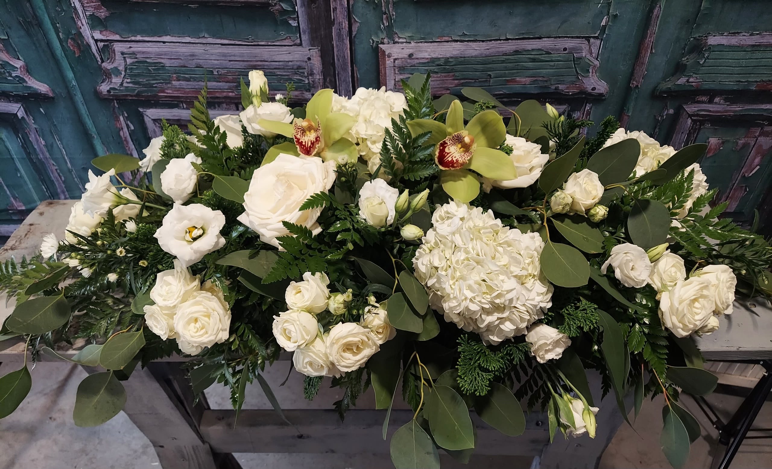 White floral arrangement with roses, hydrangea, and green orchids