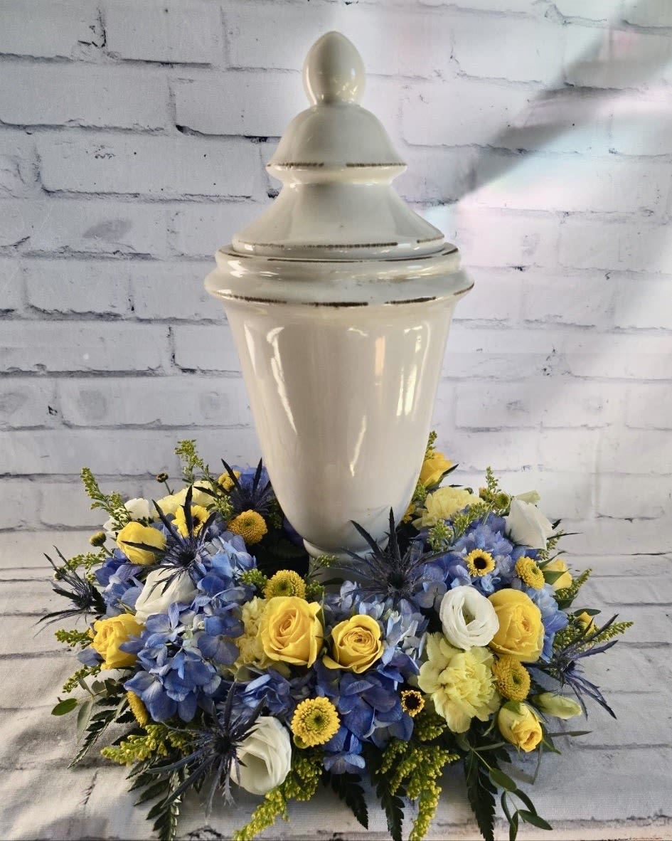 Blue and yellow floral arrangement around a white urn