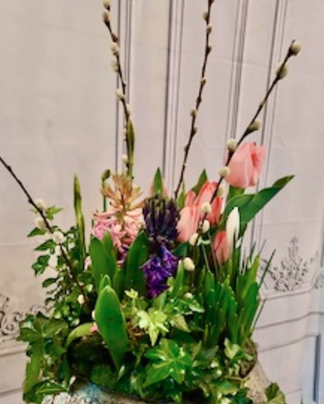 Tall floral arrangement with pink tulips, purple blooms, and pussy willow branches