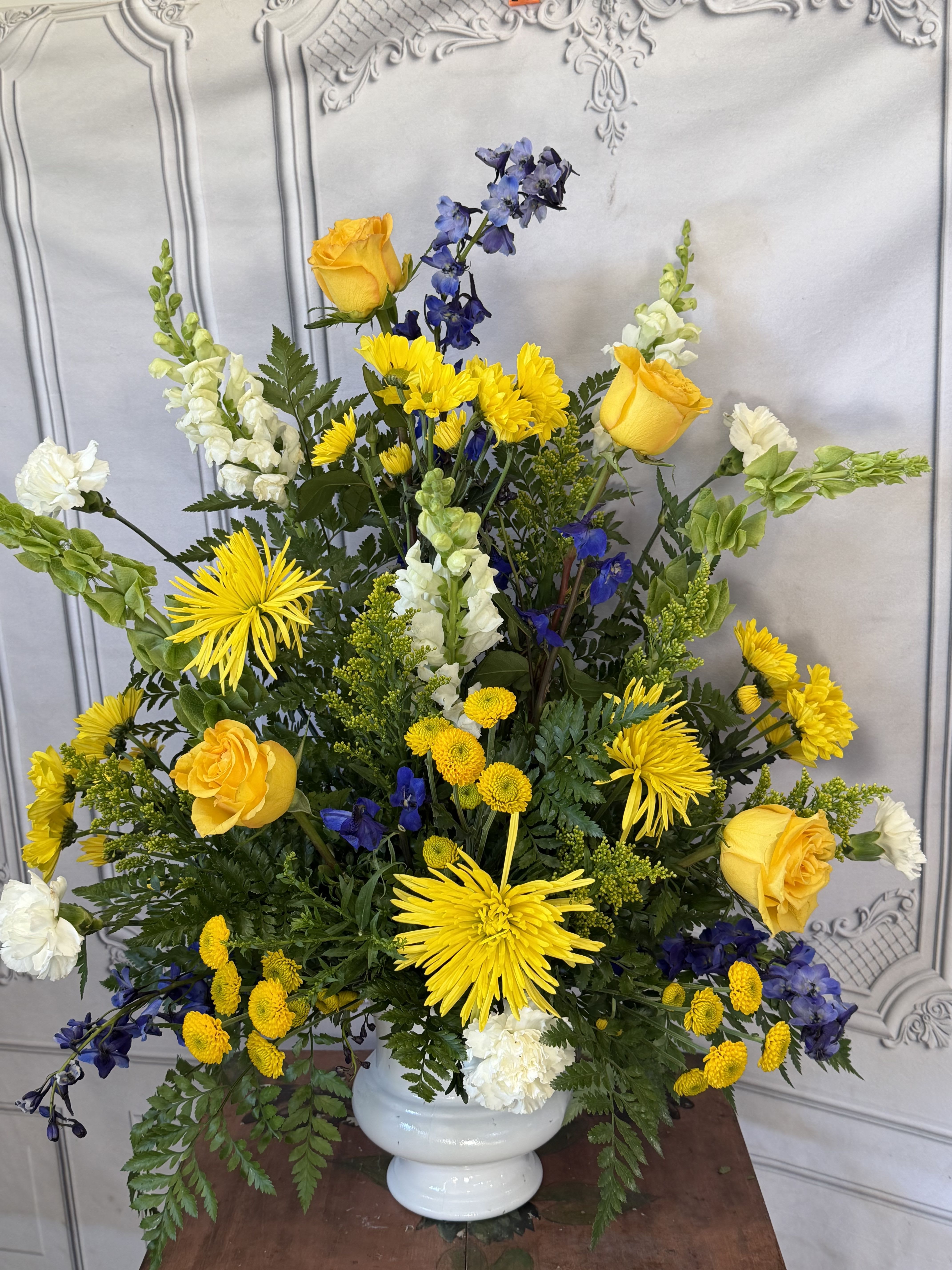 Yellow and blue floral arrangement in a white vase