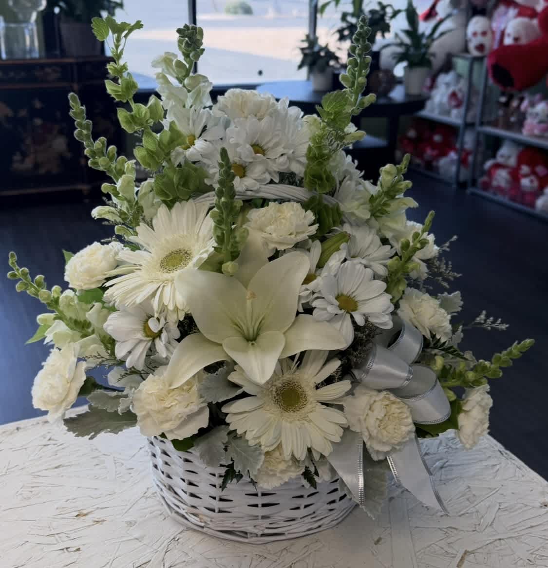 White floral basket arrangement with daisies, lilies, and carnations