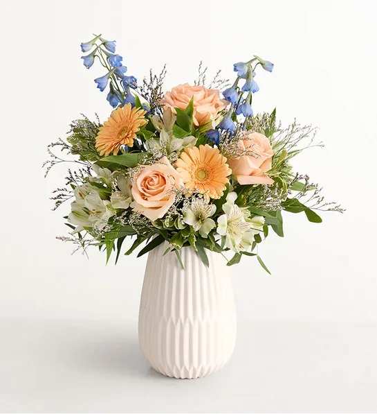 Coastal Charm™ Bouquet -  Our gathering of roses, Peruvian lilies, and other blooms evokes salt-kissed sea breezes and sunny afternoons lazing on a porch, making it an ideal gift for anyone who relishes the ease of spring and summer. Arrives in a keepsake white vase.