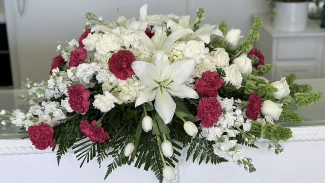White lilies and pink carnations arranged in a casket spray