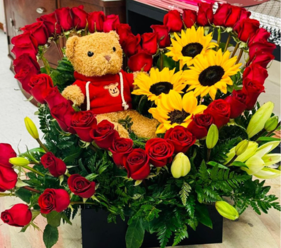 Heart-shaped rose arrangement with a teddy bear and sunflowers in a black box