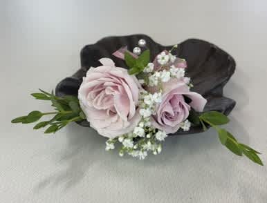Small boutonniere with pale pink roses and white baby's breath on a dark shell