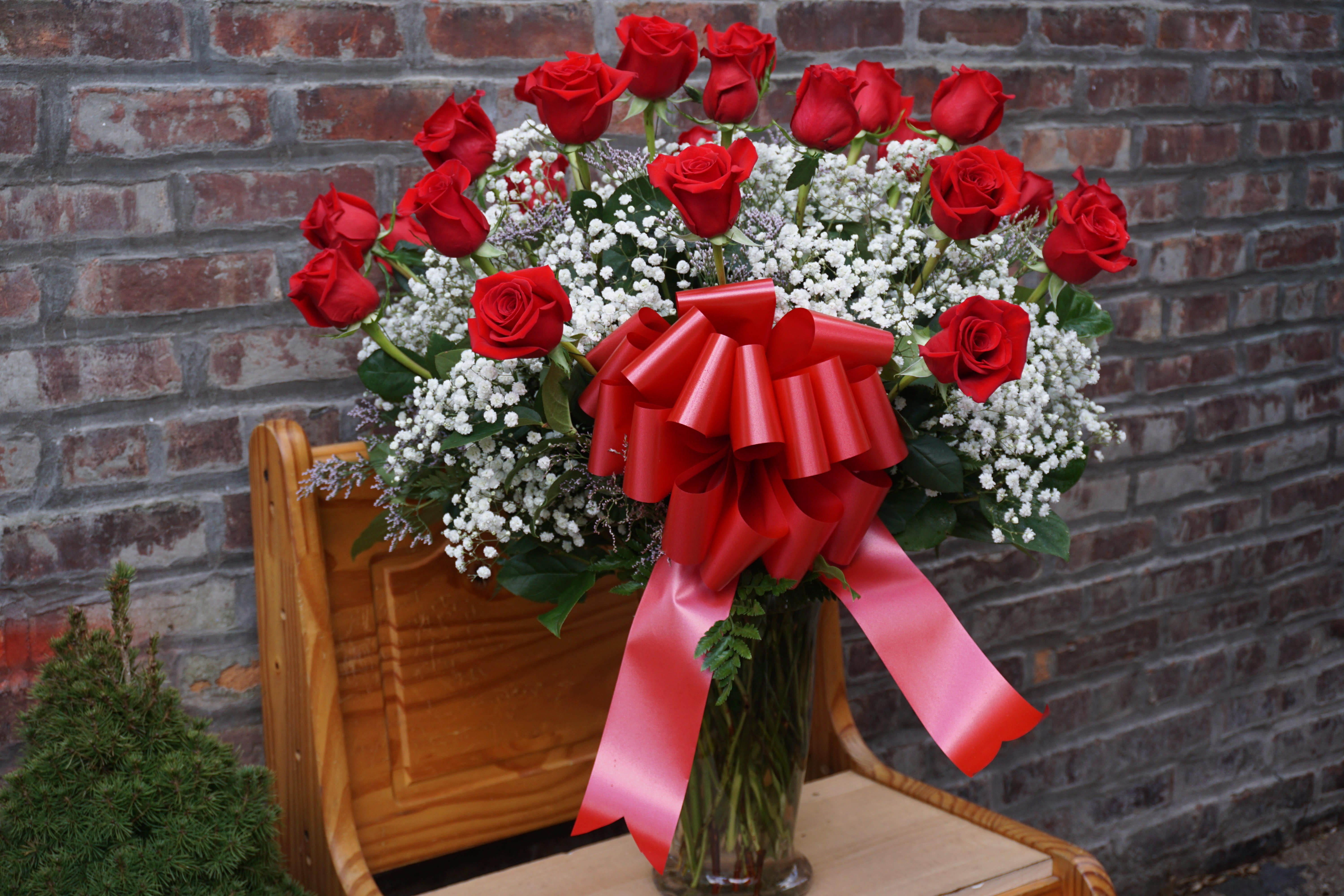 Red roses in a glass vase with white baby's breath and a red bow
