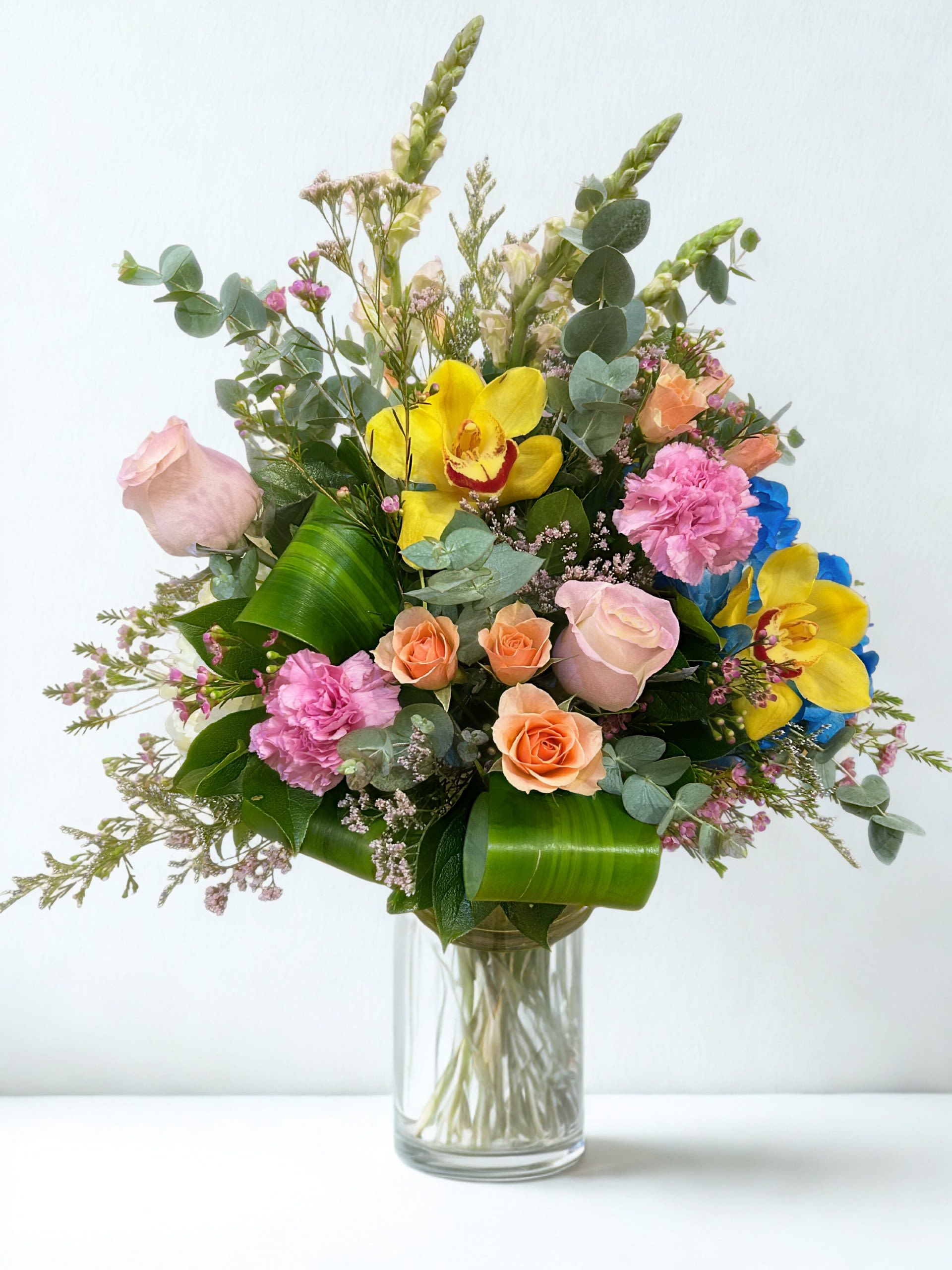 Mixed bouquet of roses, orchids, and carnations in a glass vase