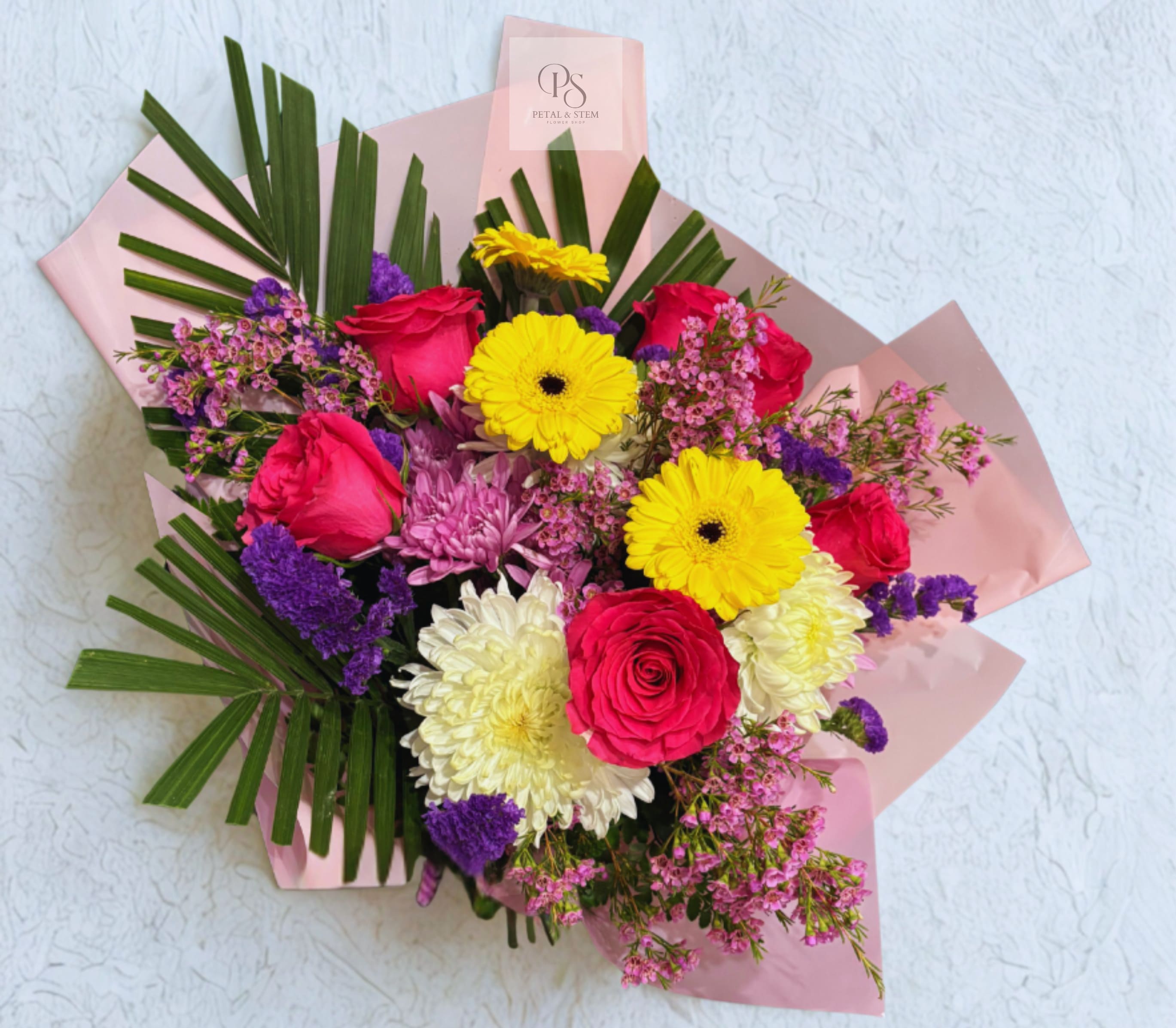 Mixed bouquet of roses, gerbera daisies, and chrysanthemums wrapped in pink paper