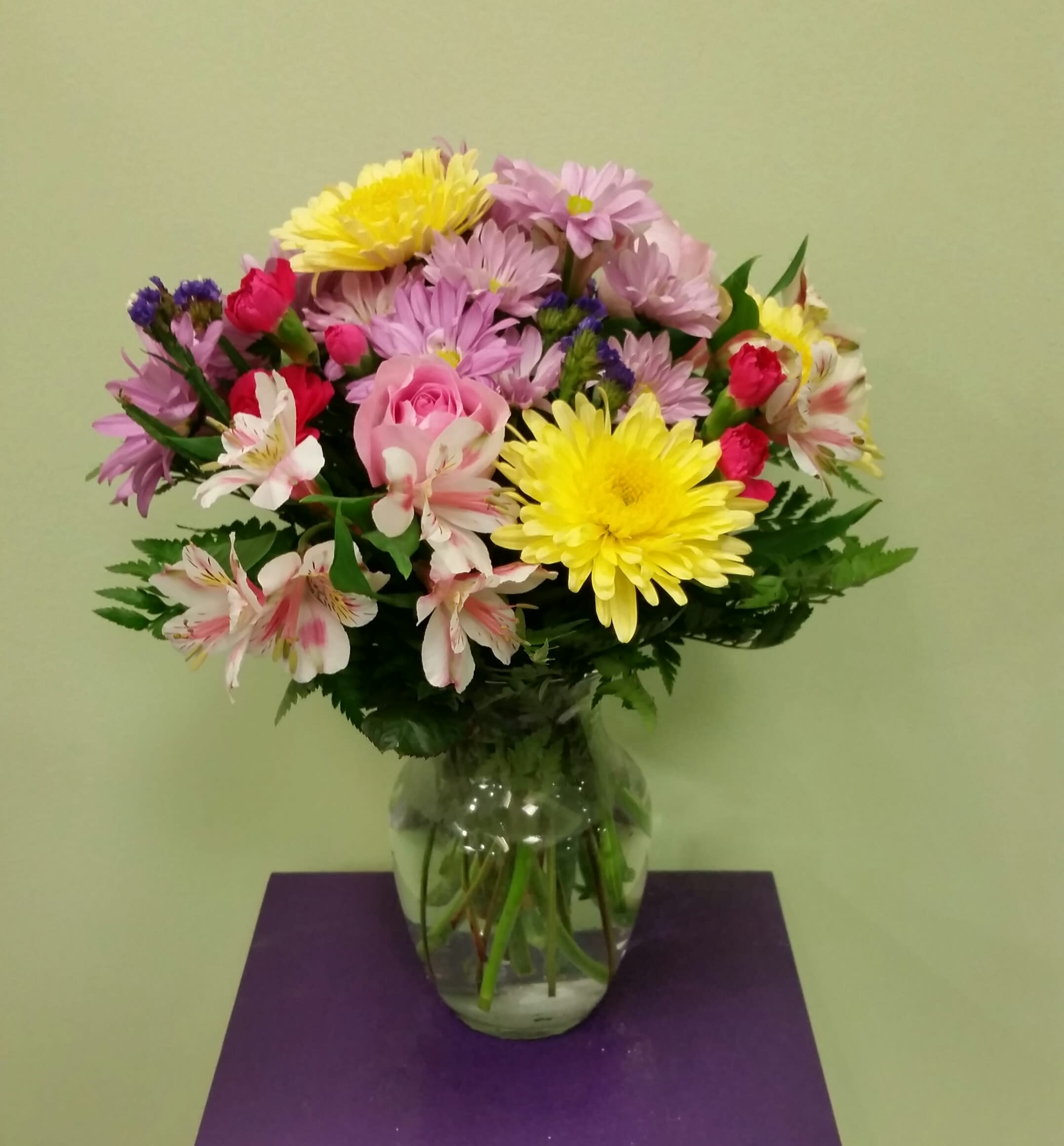 Mixed bouquet of daisies, roses, and alstroemeria in a glass vase