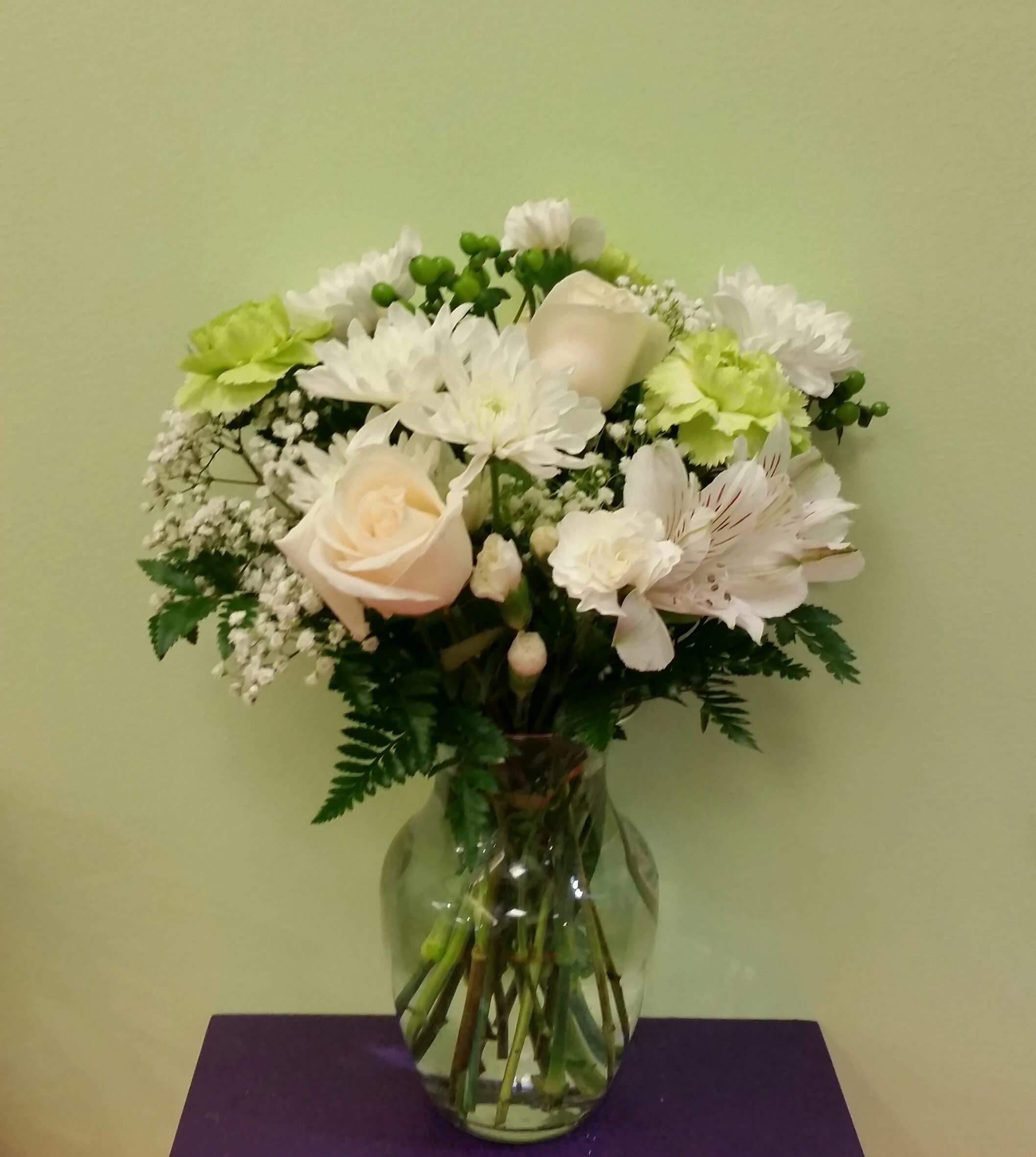 White and pale peach flowers arranged in a clear glass vase