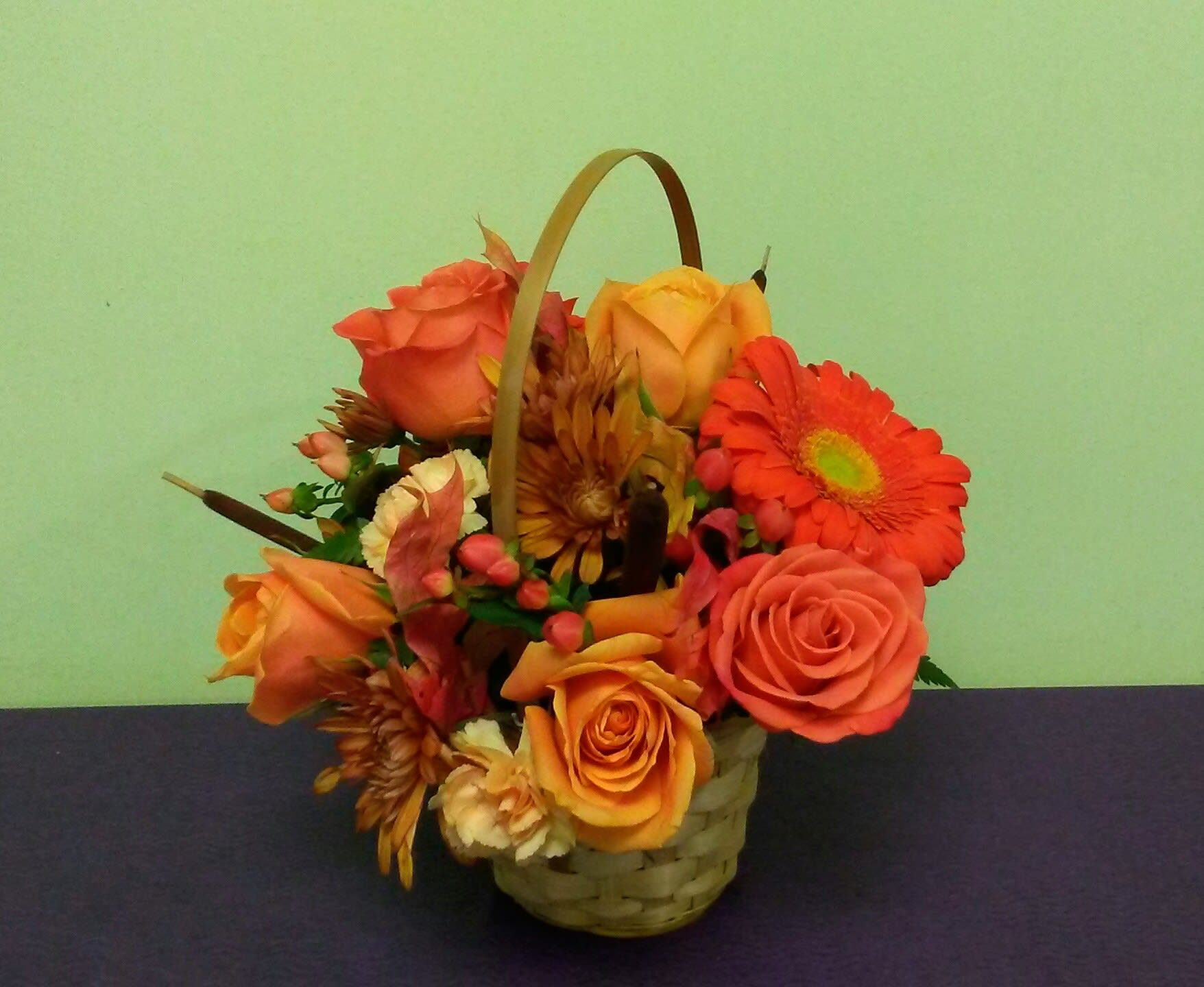 Basket arrangement of orange roses and gerbera daisies