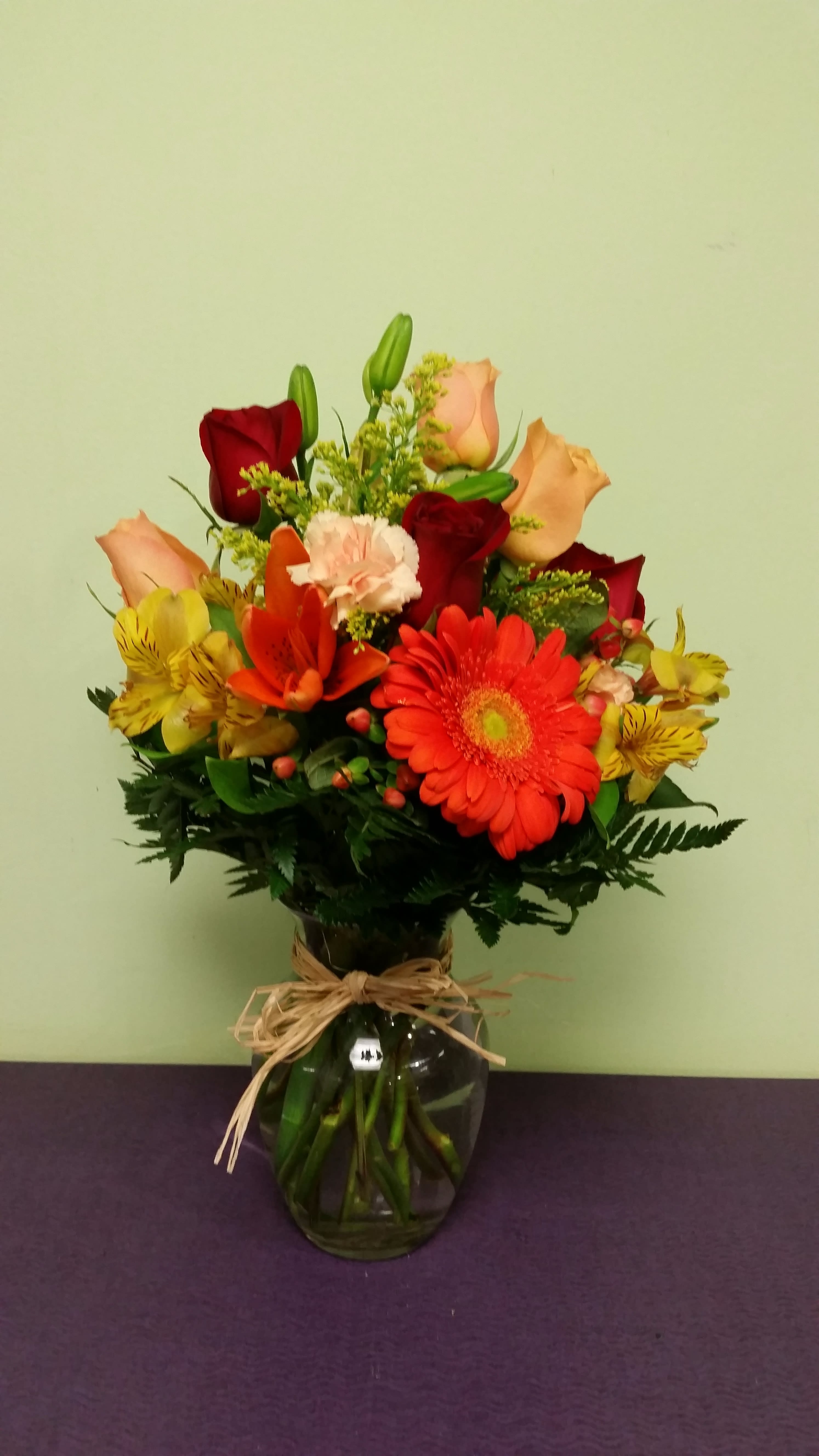 Mixed bouquet of roses, gerbera daisies, lilies, and alstroemeria in a glass vase