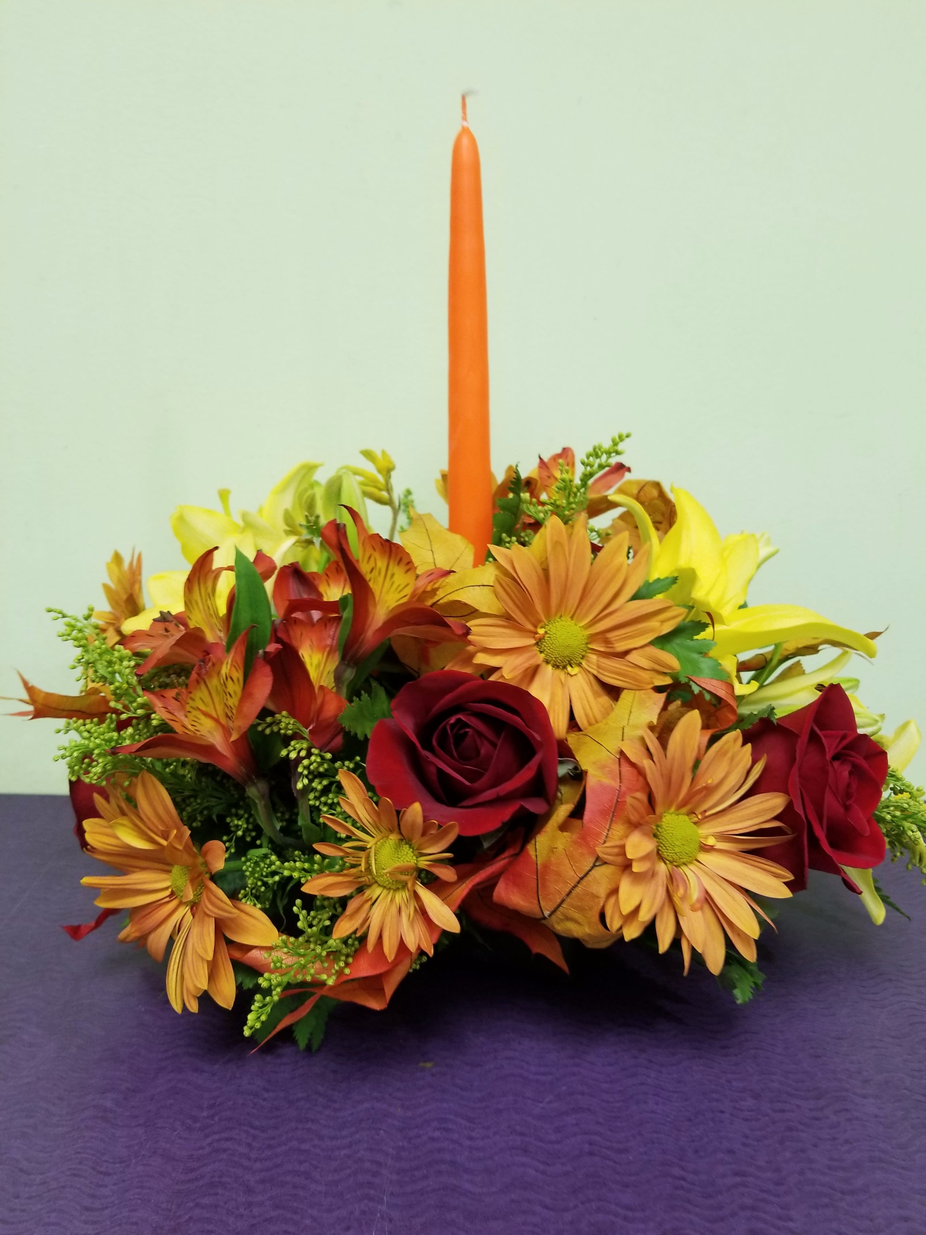 Autumn floral centerpiece with an orange taper candle