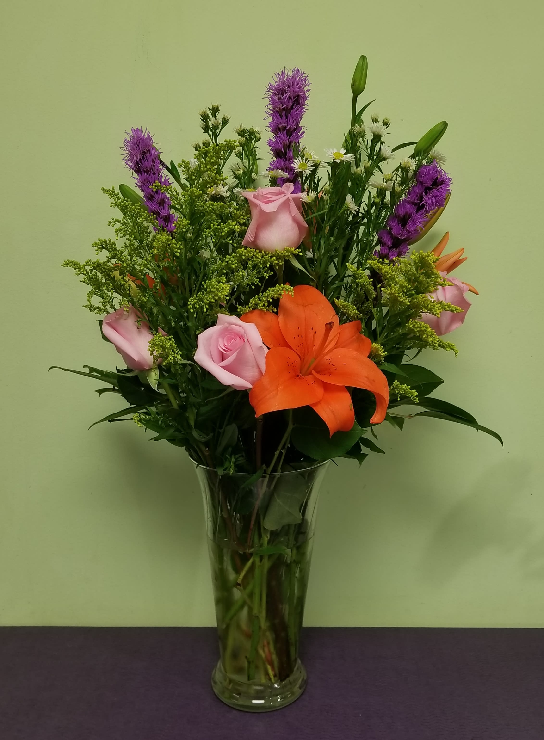 Bouquet of orange lilies and pink roses in a clear glass vase